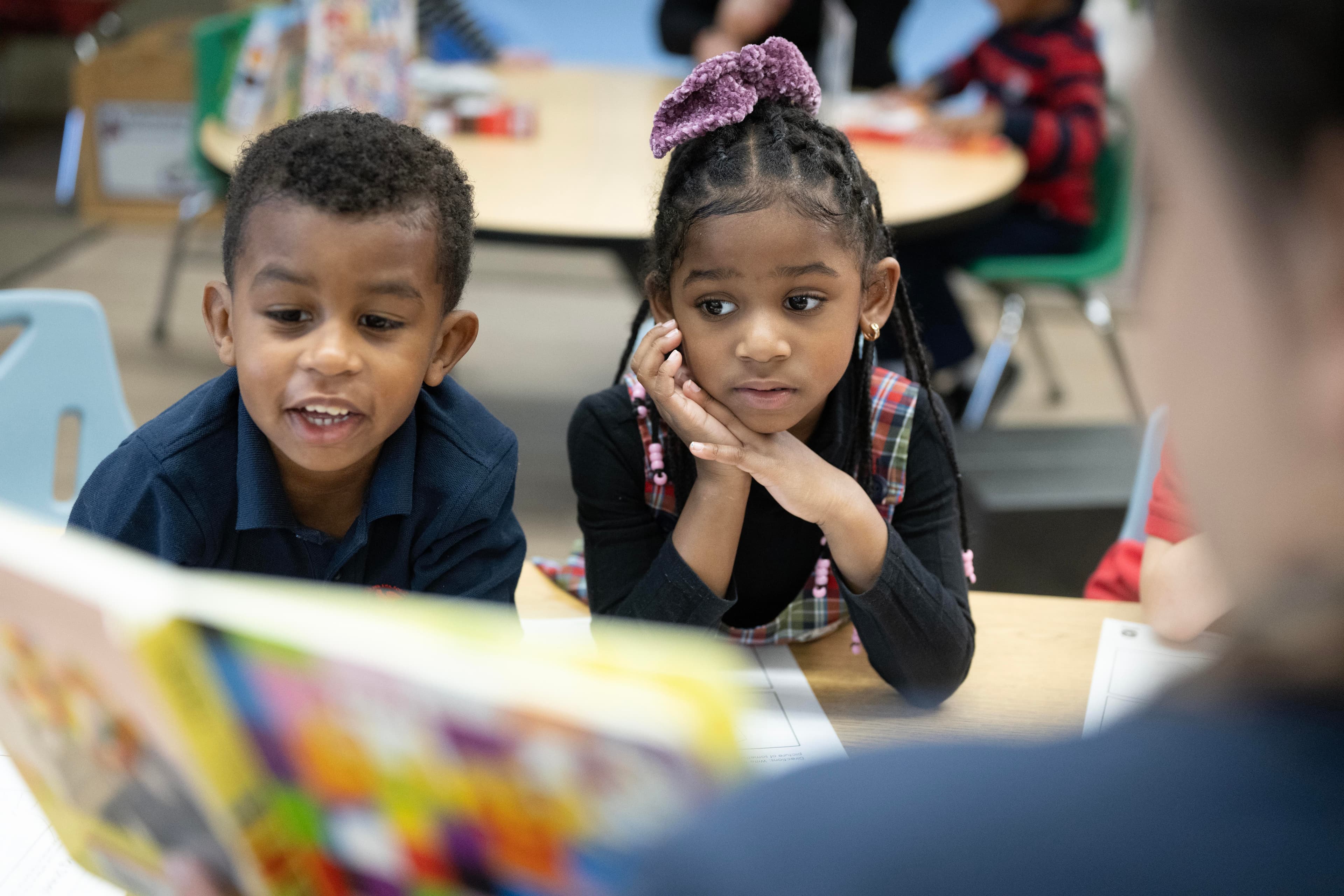two children being read to by a teacher