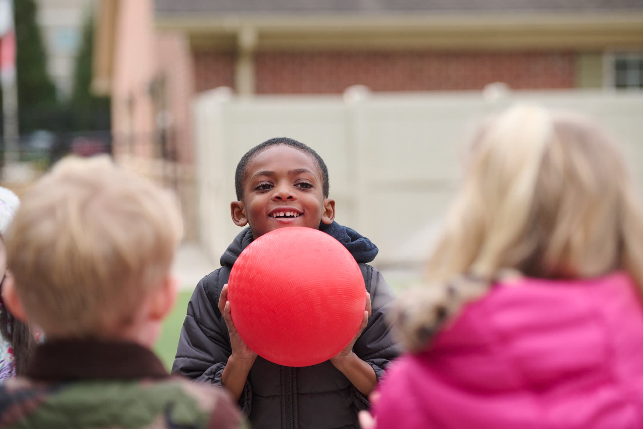 kindergarten child playing outside holding a ball